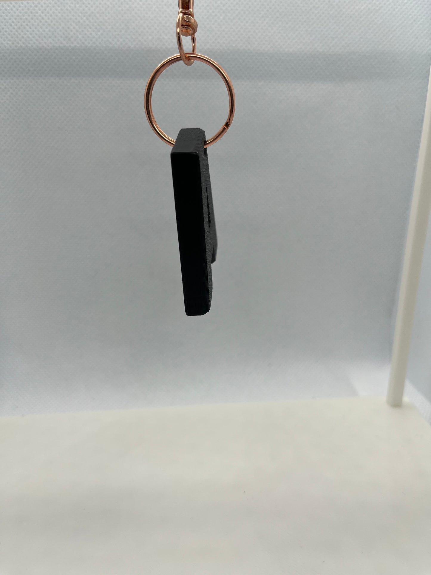 Black keychain device attached to a gold ring on a white background