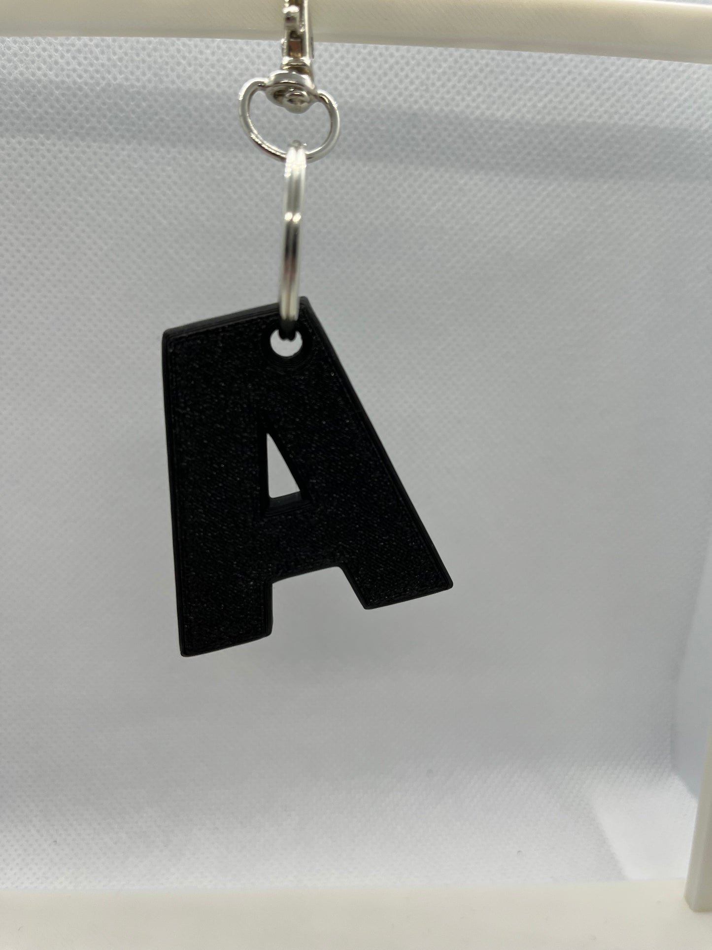 Black keychain letter 'A' on a white background
