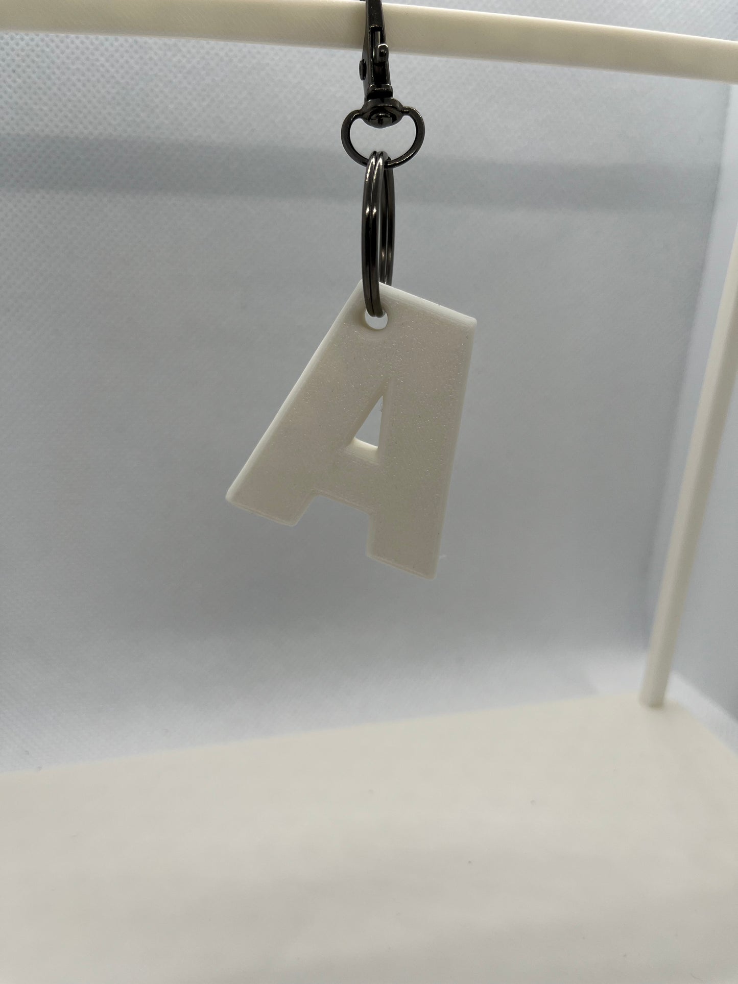 White letter 'A' keychain attached to a keyring on a white background