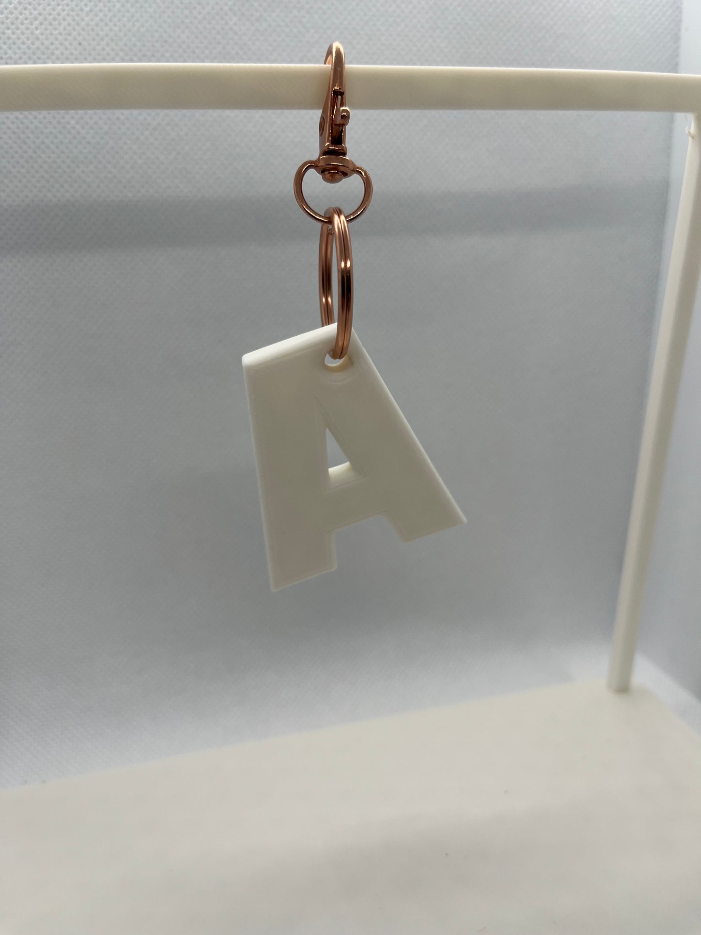 White letter 'A' keychain with rose gold ring on a white background