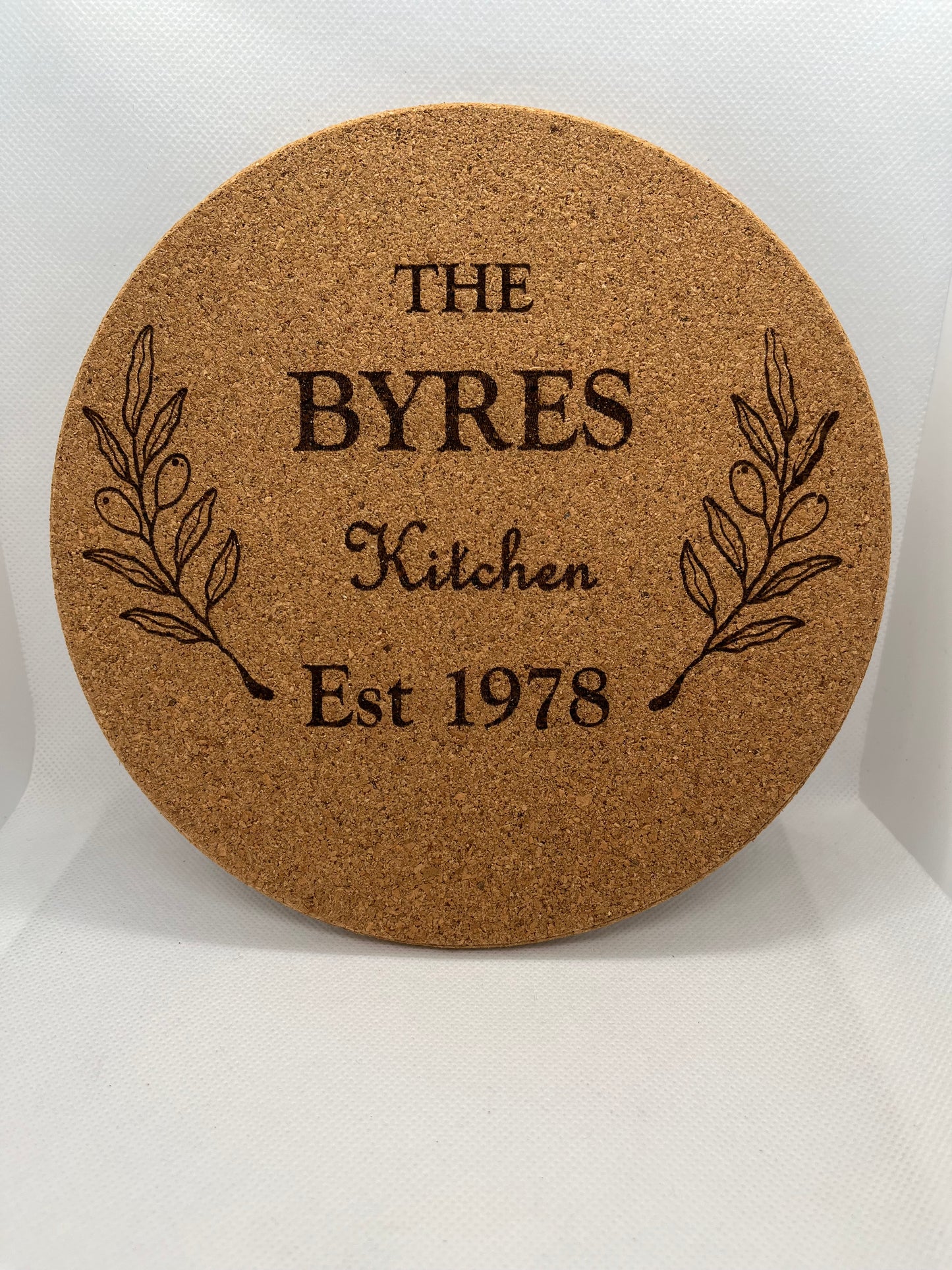 Round cork coaster with engraved text and leaf design on a white background