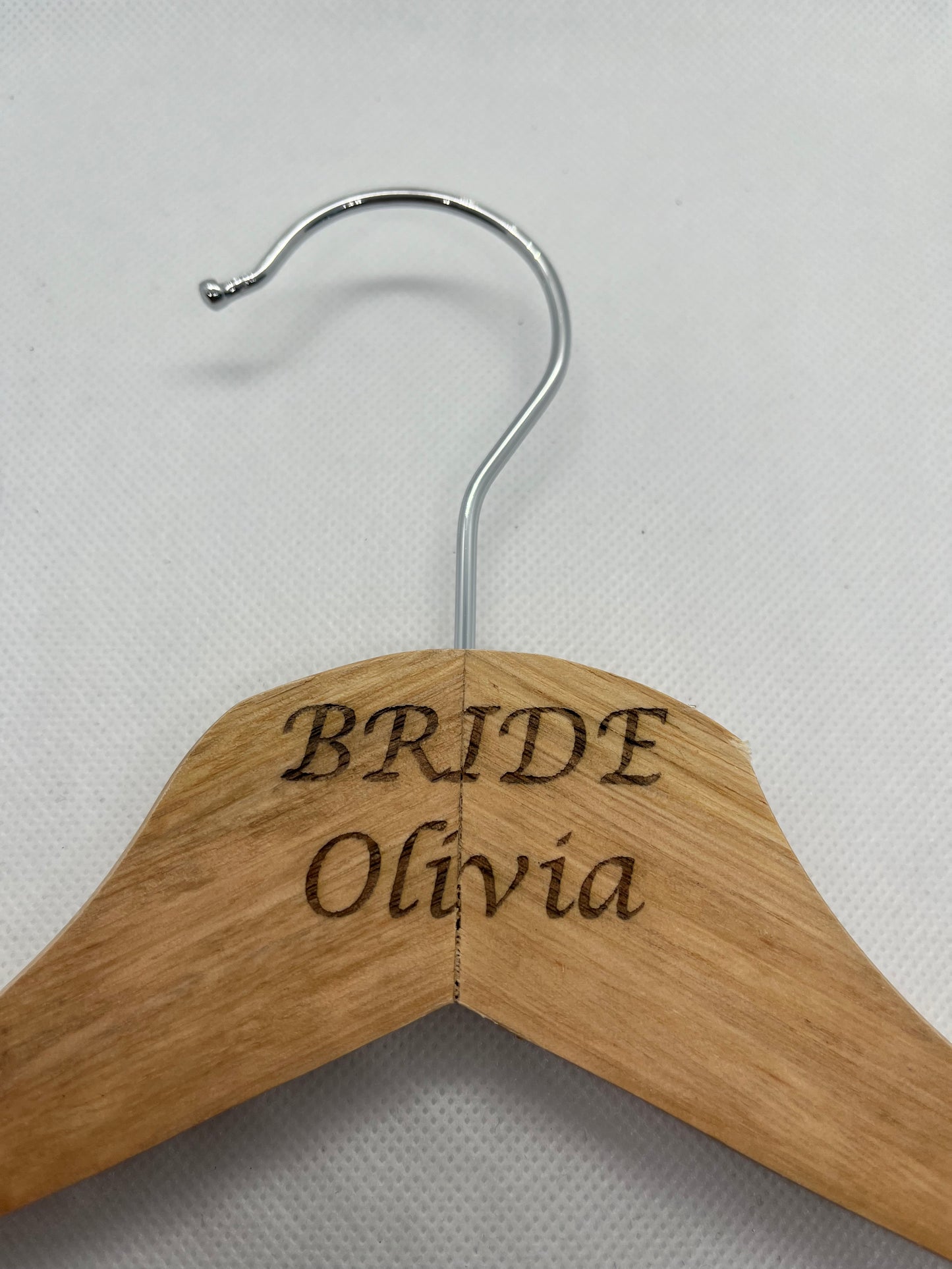 Wooden hanger with engraved text on a light gray background
