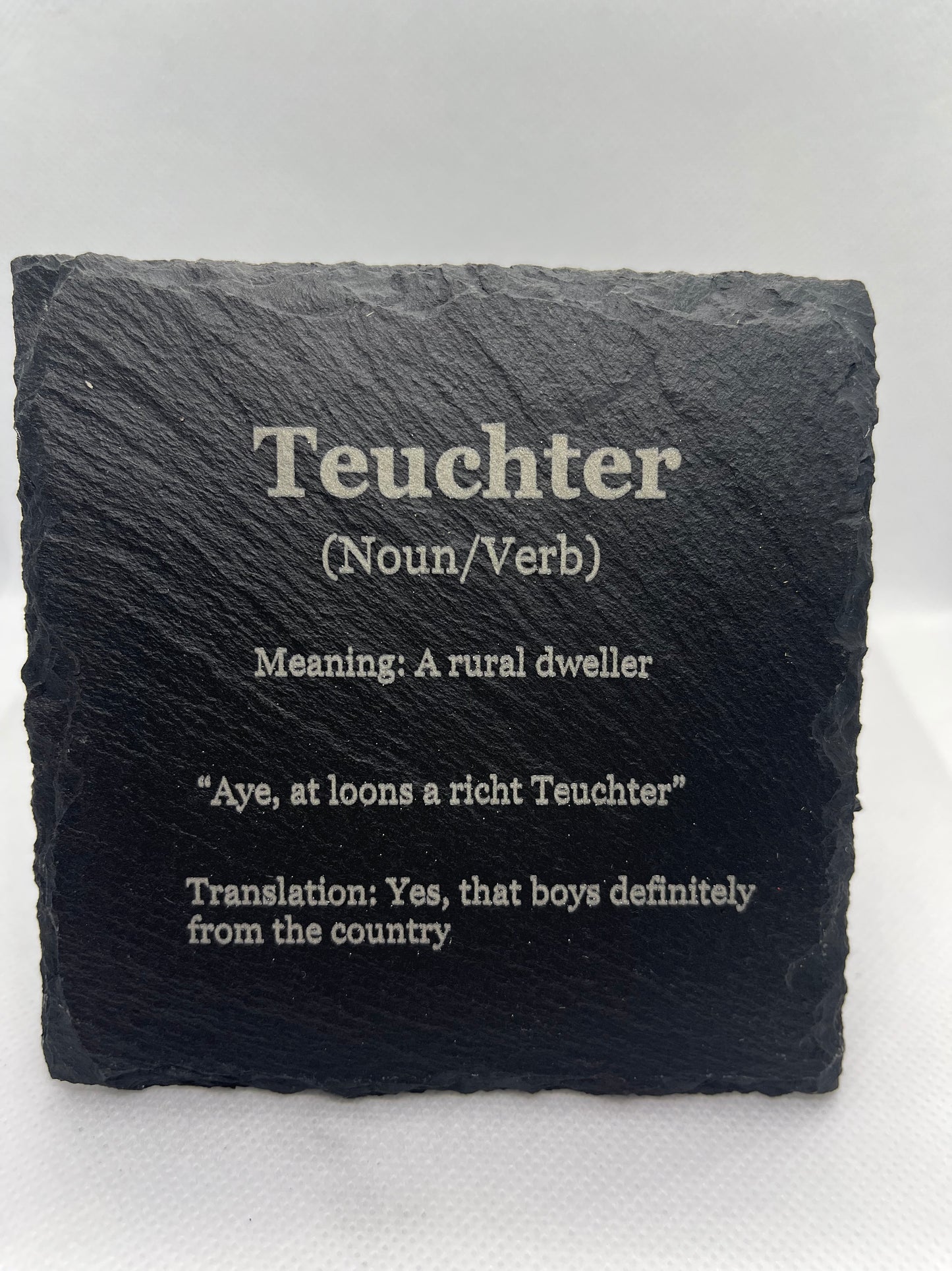 Slate coaster with engraved definition of 'Teuchter' on a white background