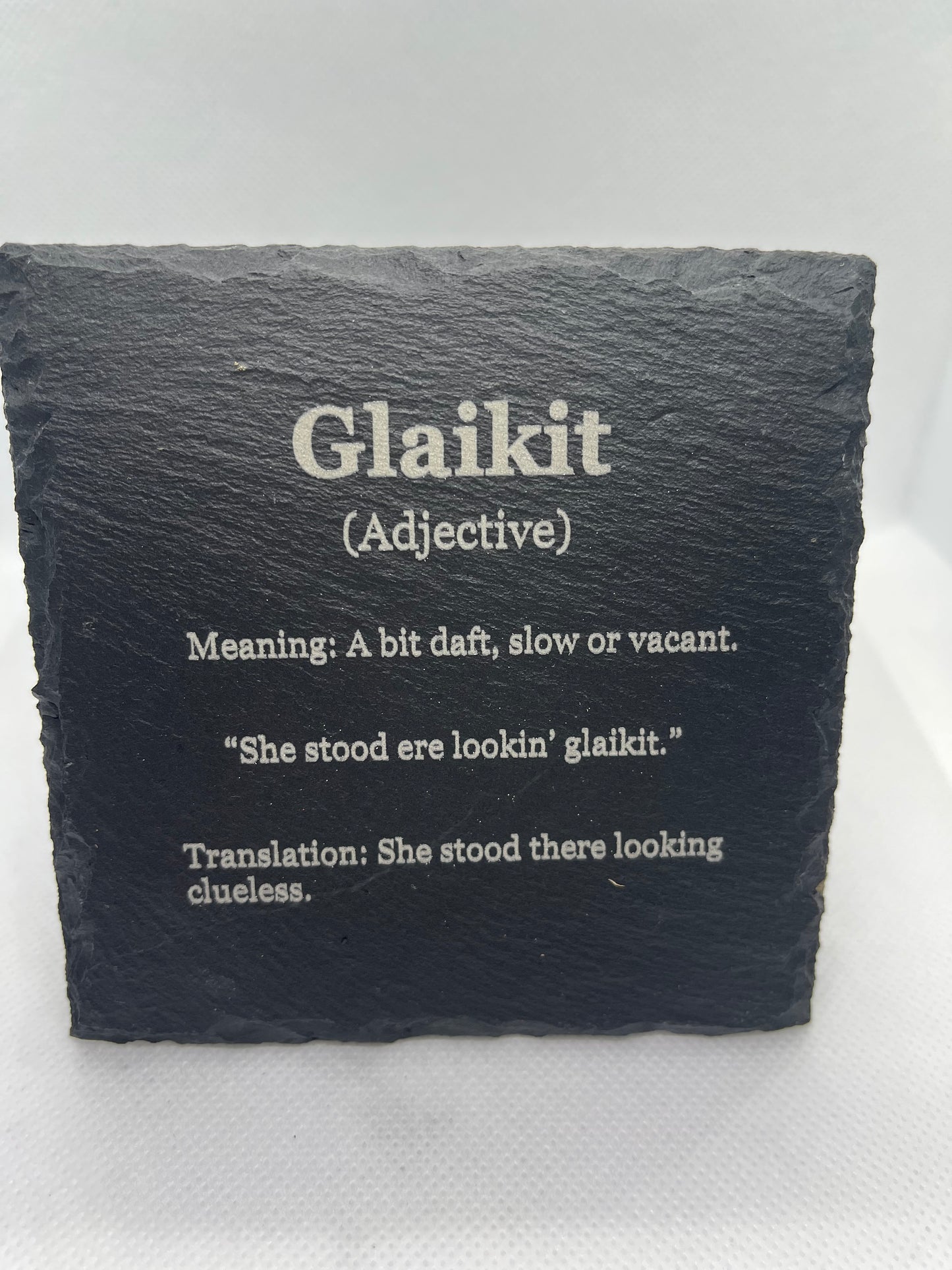 Slate coaster with engraved text on a white background