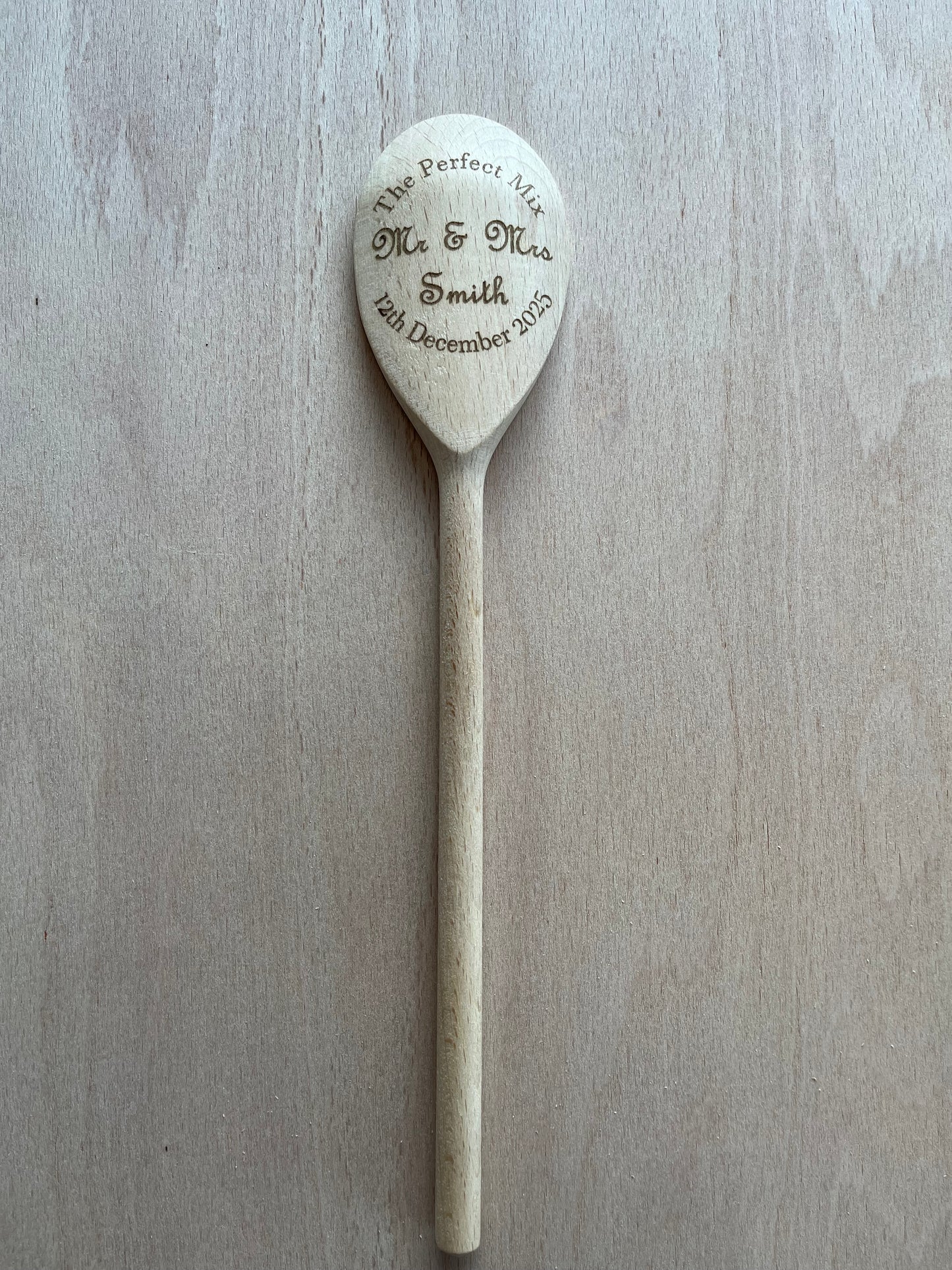 Wooden spoon with engraved text on a light wooden surface