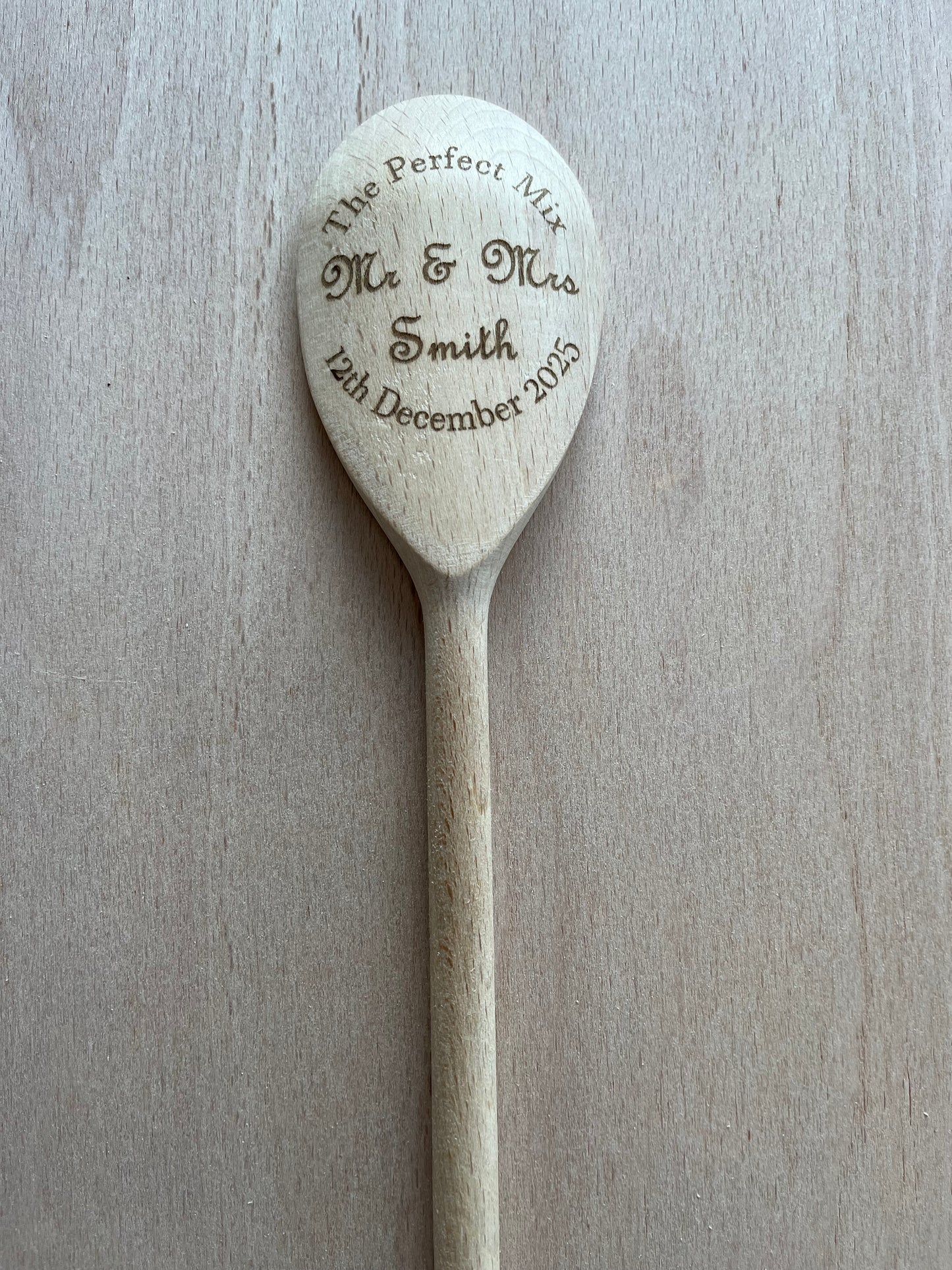 Wooden spoon with engraved text on a light wooden surface