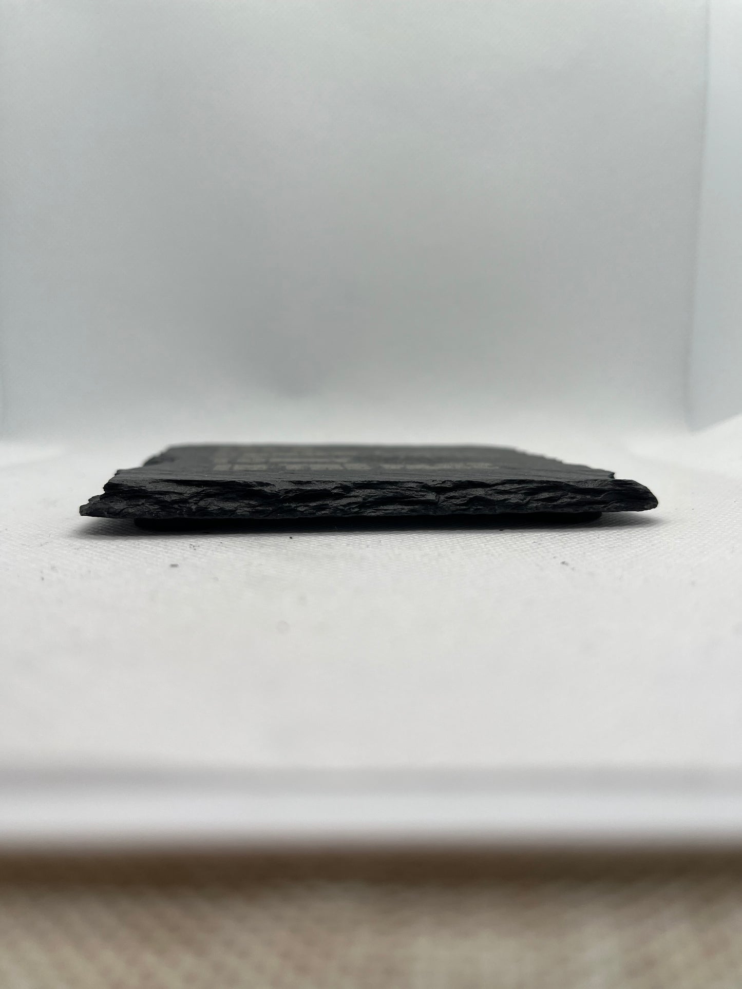 side-view-of-a-Black rectangular slate coaster on a white surface