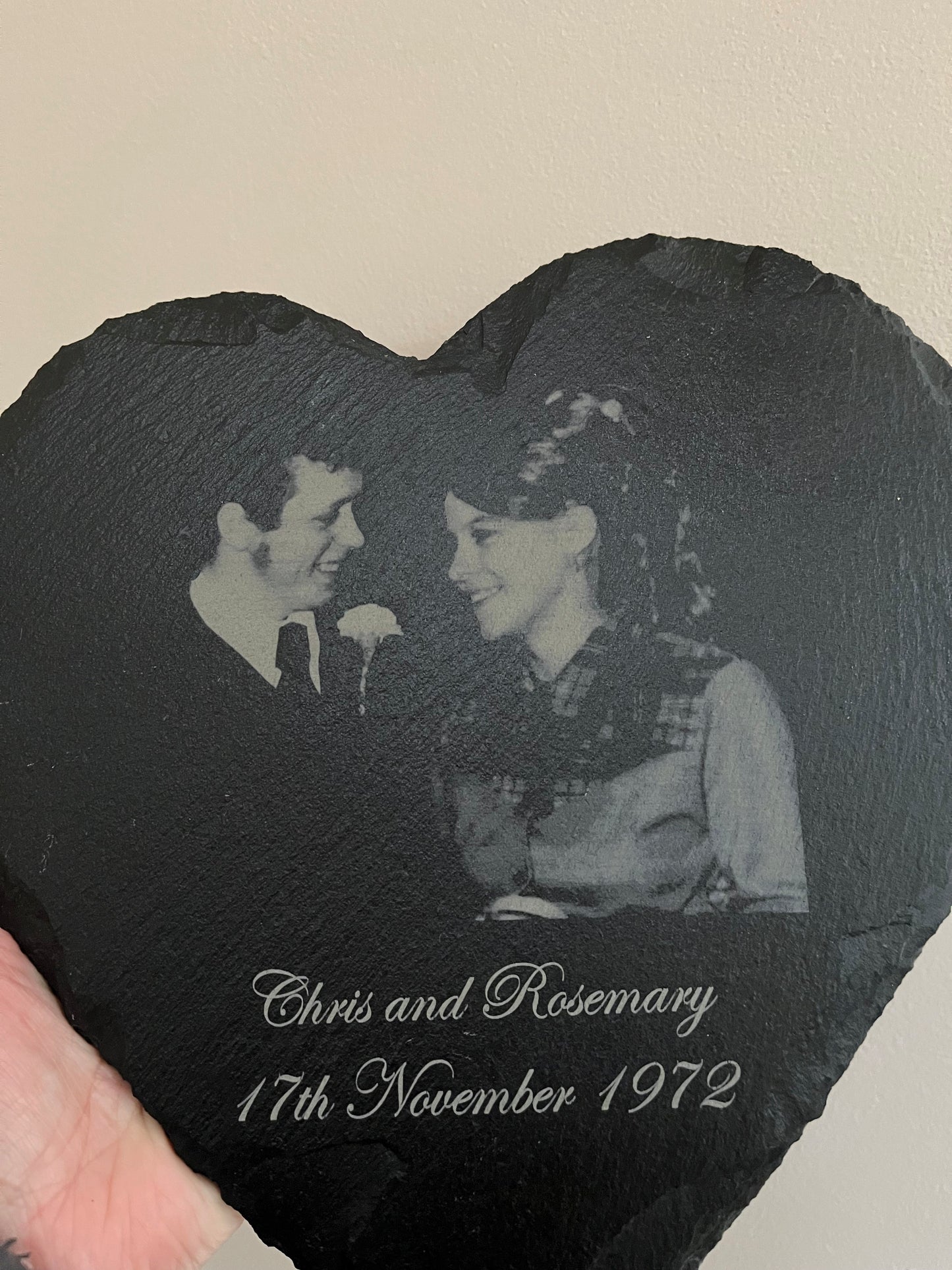 Heart-shaped slate with engraved photo of a couple and text on a beige background