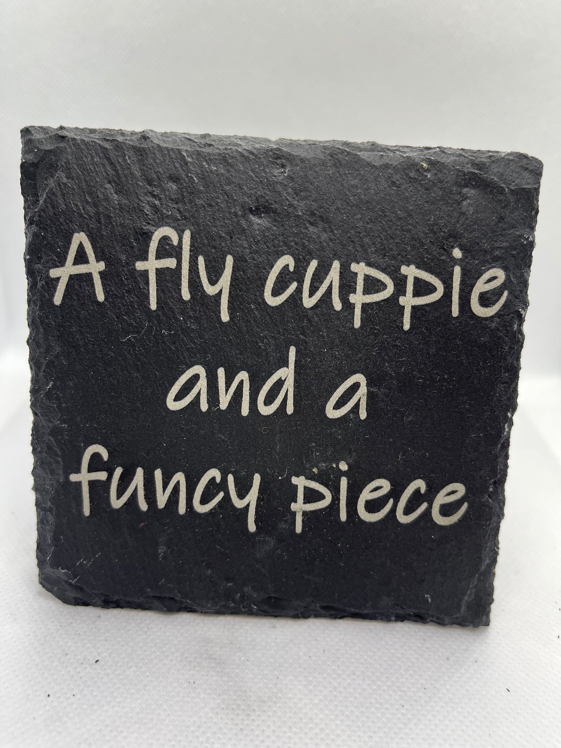 Black slate coaster with white text on a white background
