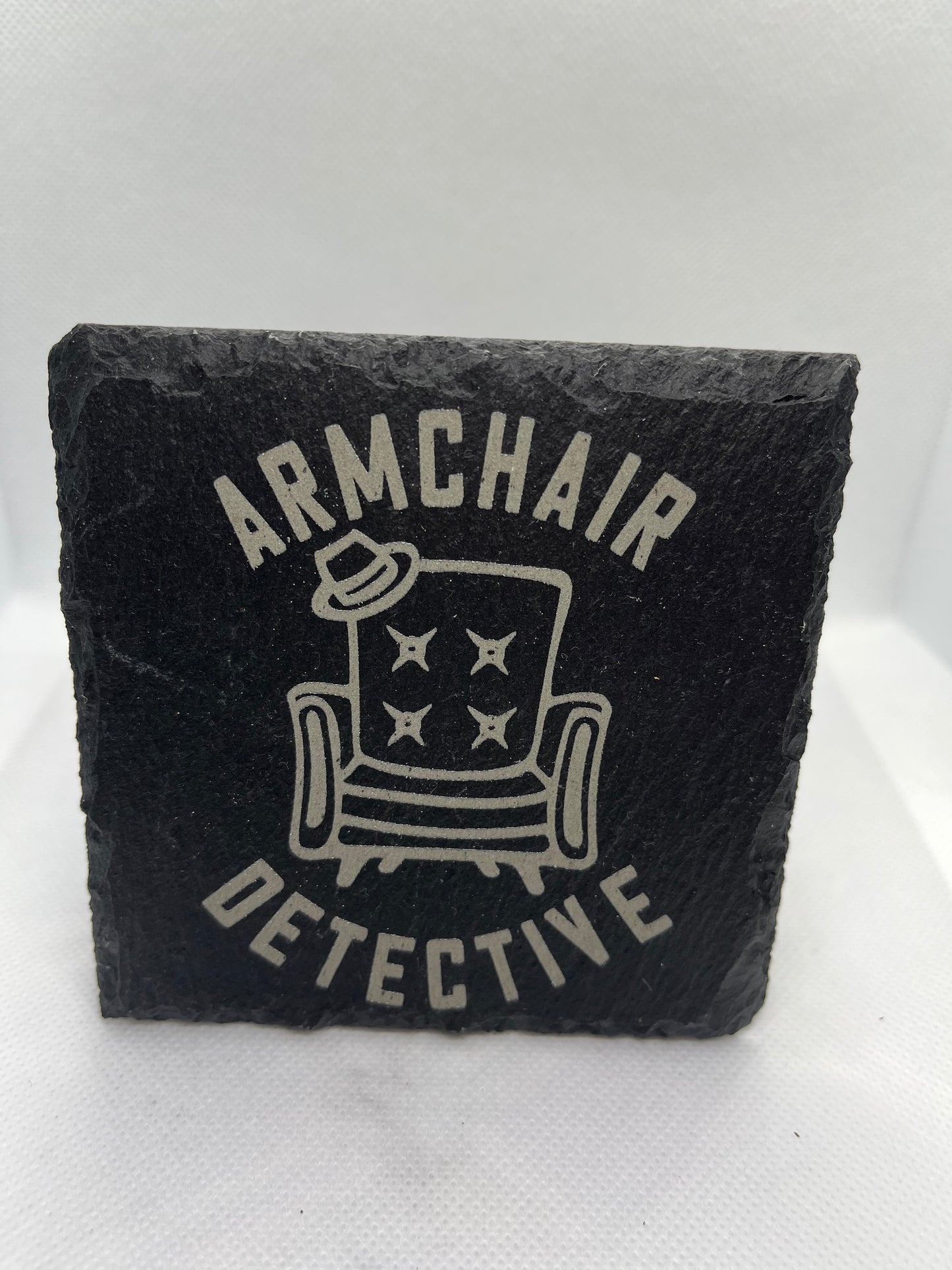 Black slate coaster with 'Armchair Detective' design on a white background