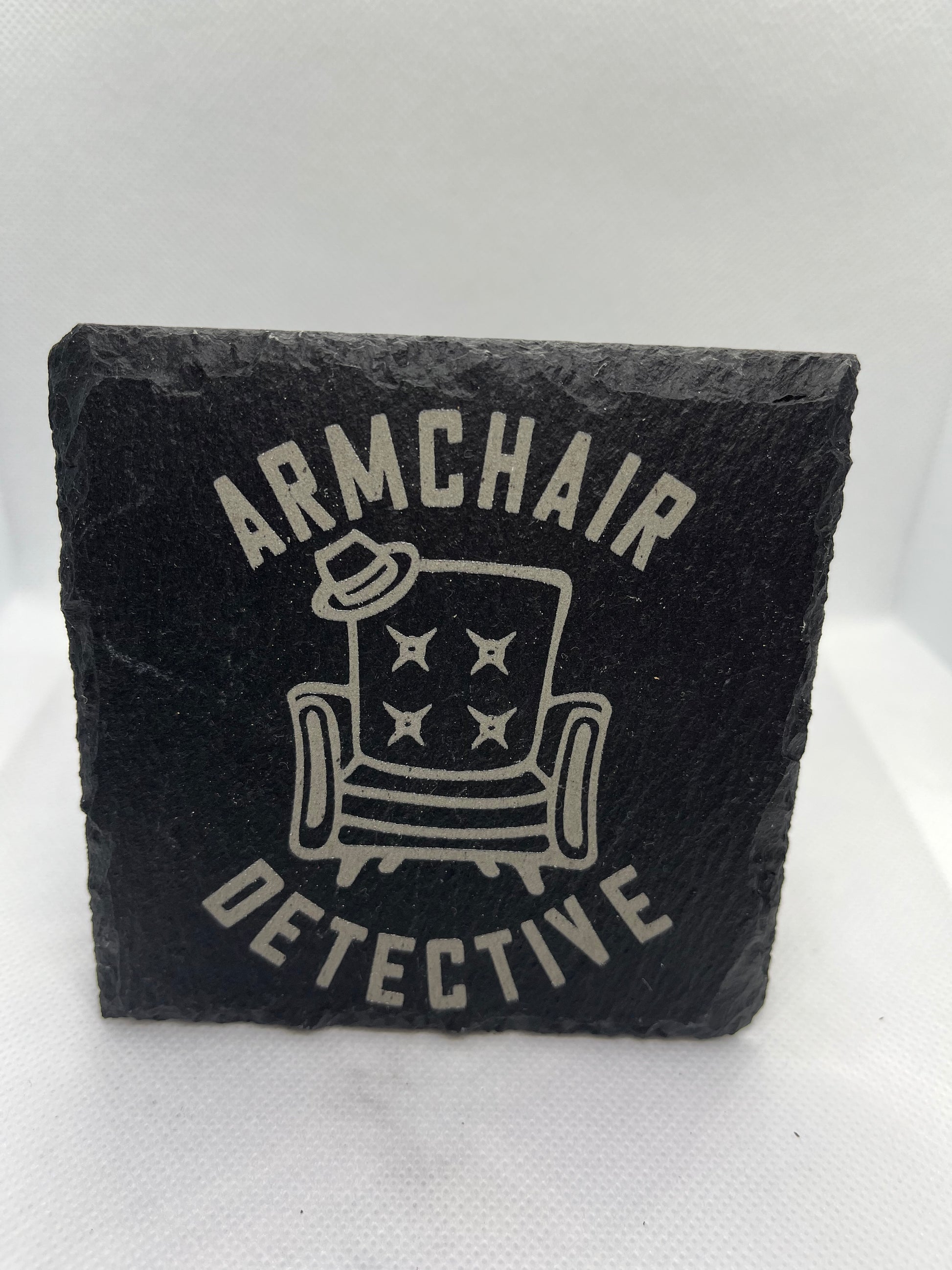 Black slate coaster with 'Armchair Detective' design on a white background