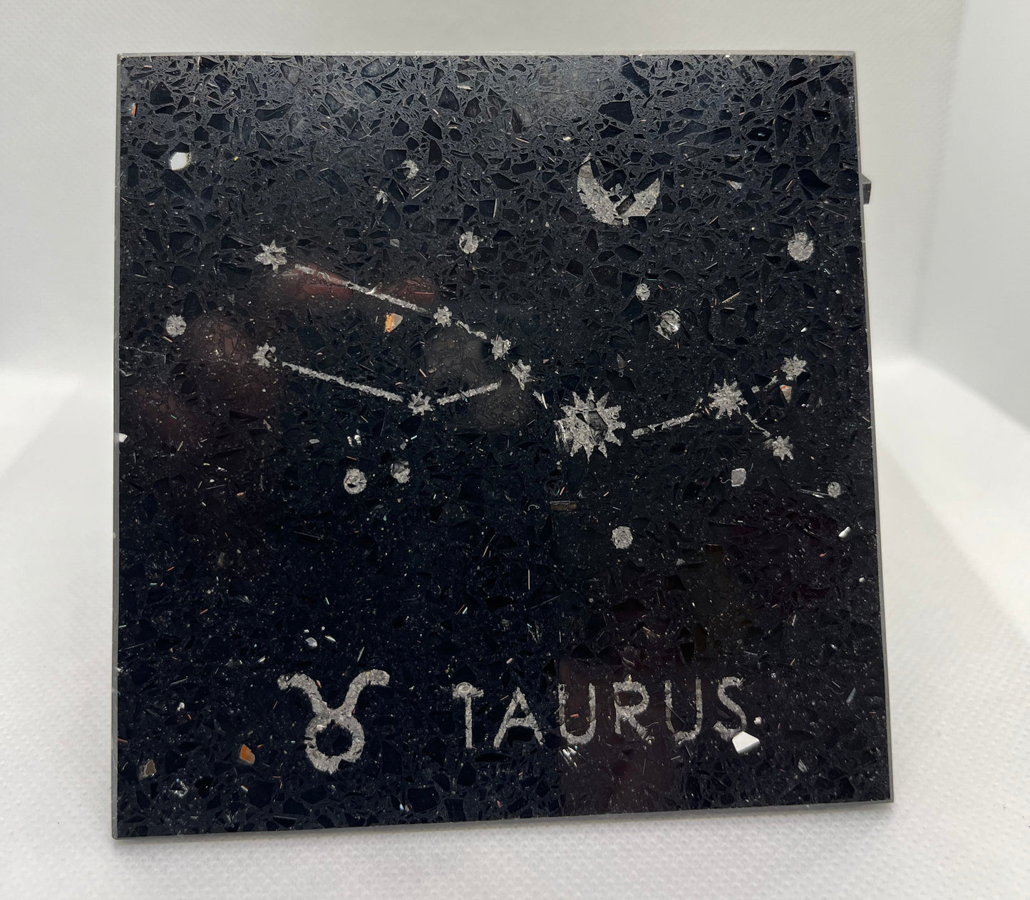 Decorative tile with Taurus constellation design on a black background