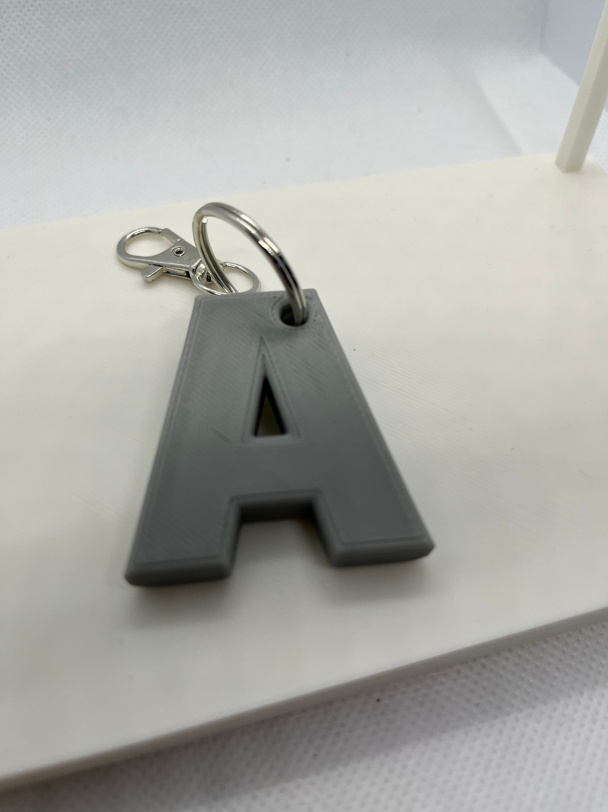Gray keychain with a letter 'A' on a white surface