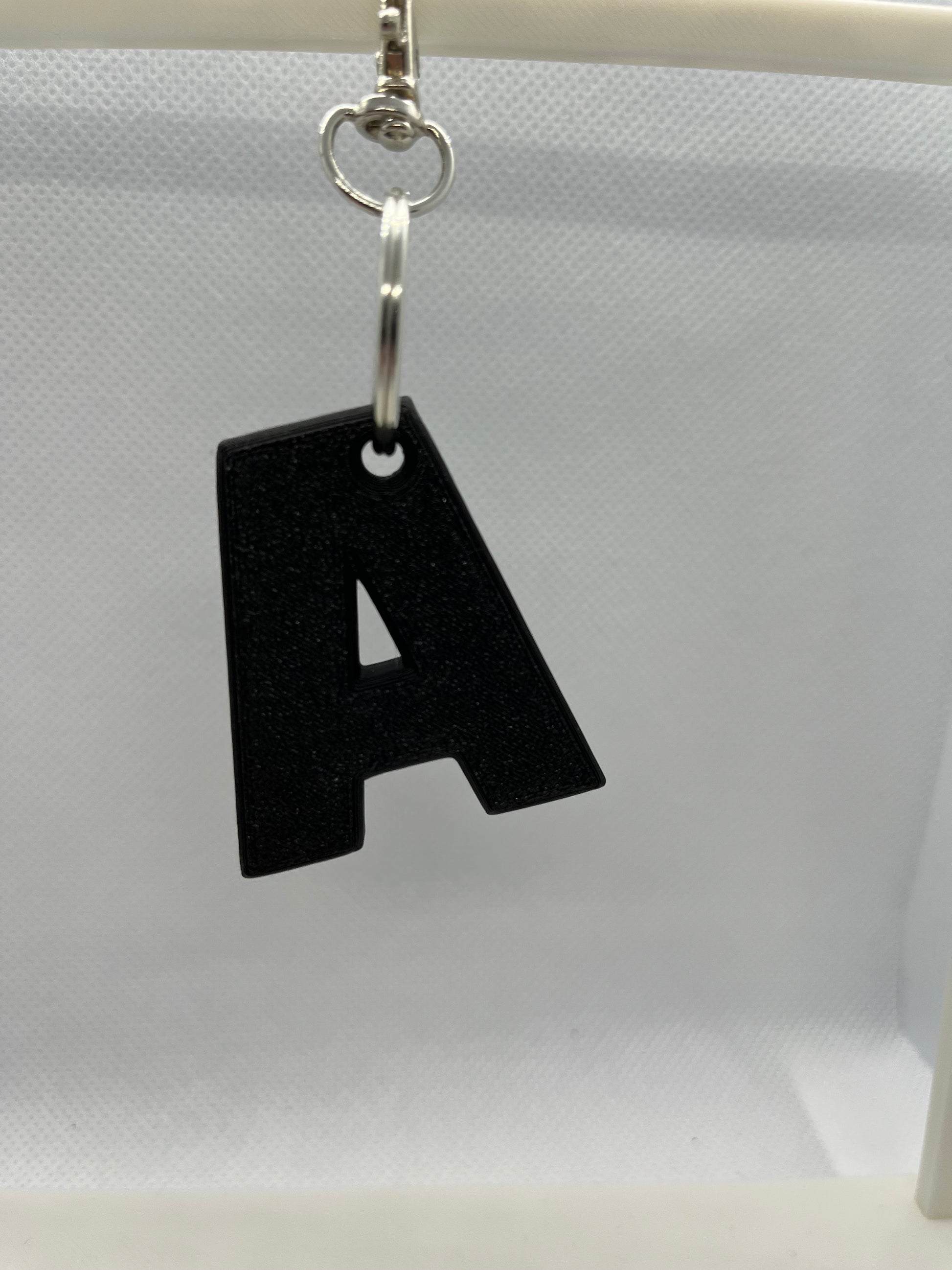 Black keychain letter 'A' on a white background