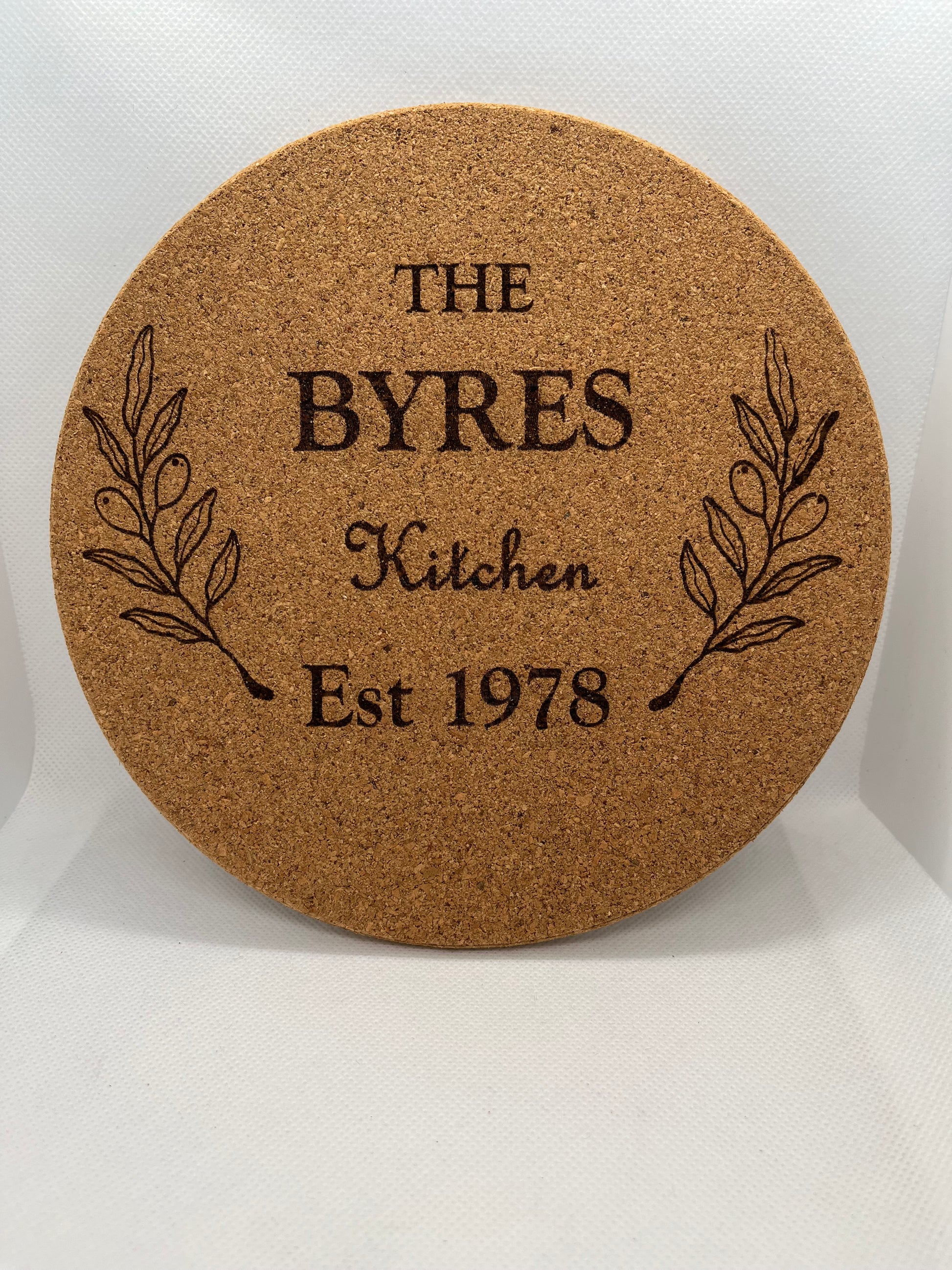 Round cork coaster with engraved text and leaf design on a white background