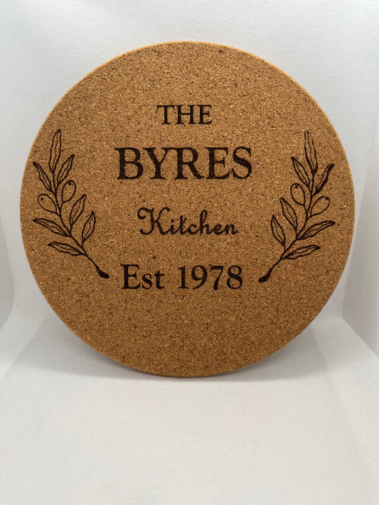Round cork coaster with engraved text and leaf design on a white background