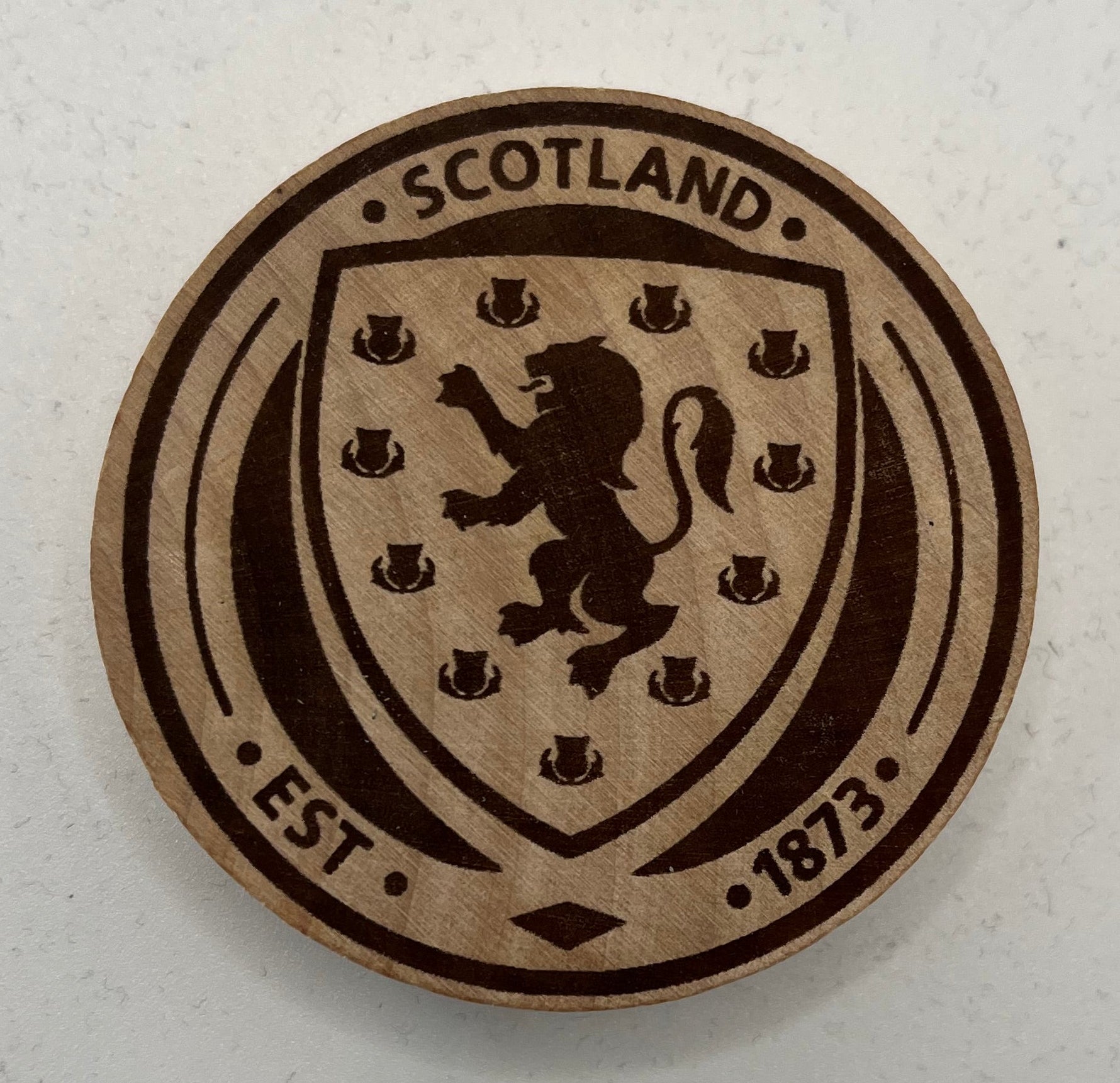 Round wooden coaster with a design of a lion and text on a white background