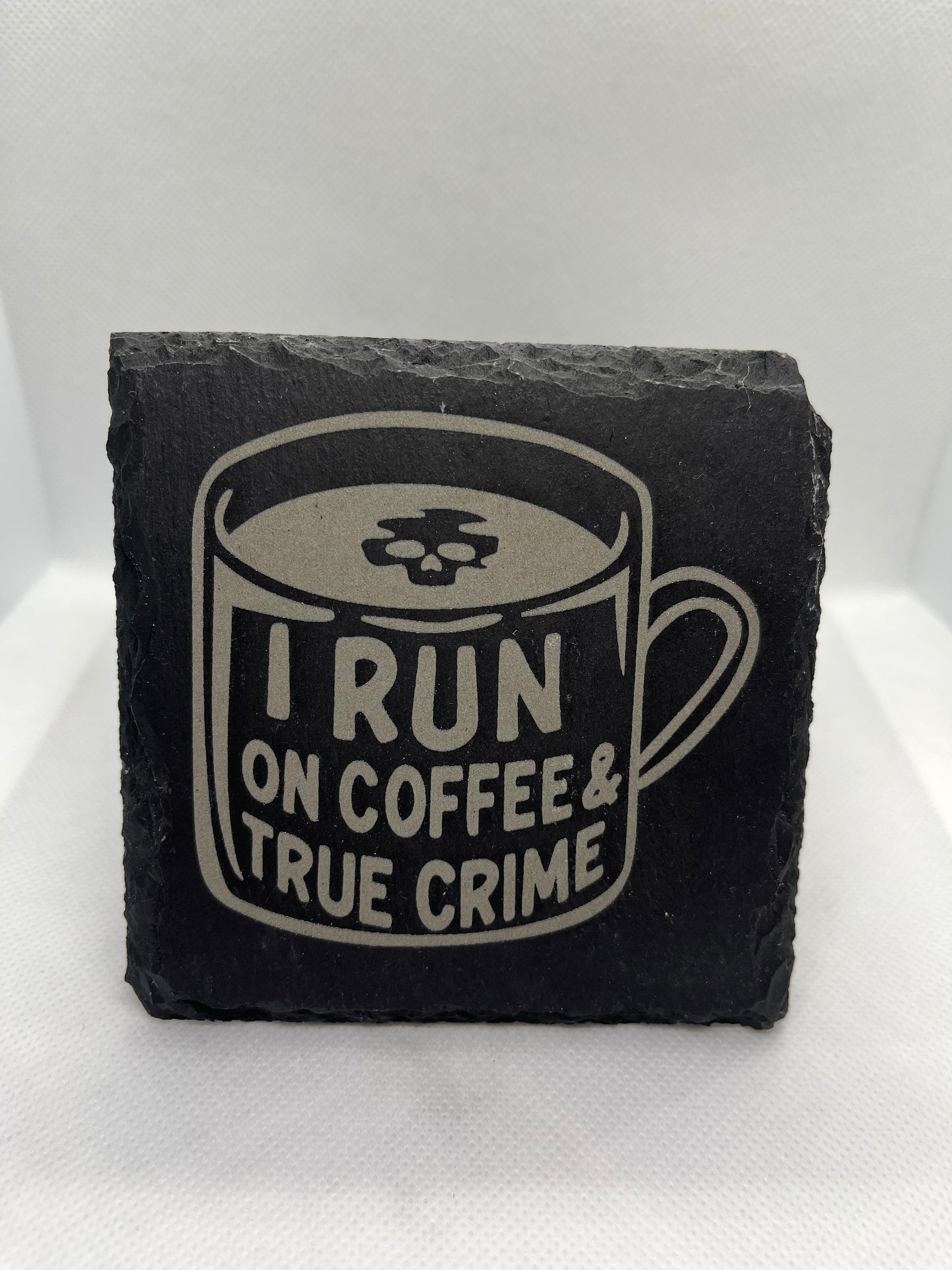Black slate coaster with 'I Run on Coffee & True Crime' design on a white background