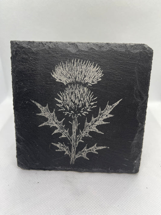 Slate coaster with engraved thistle design on a white background