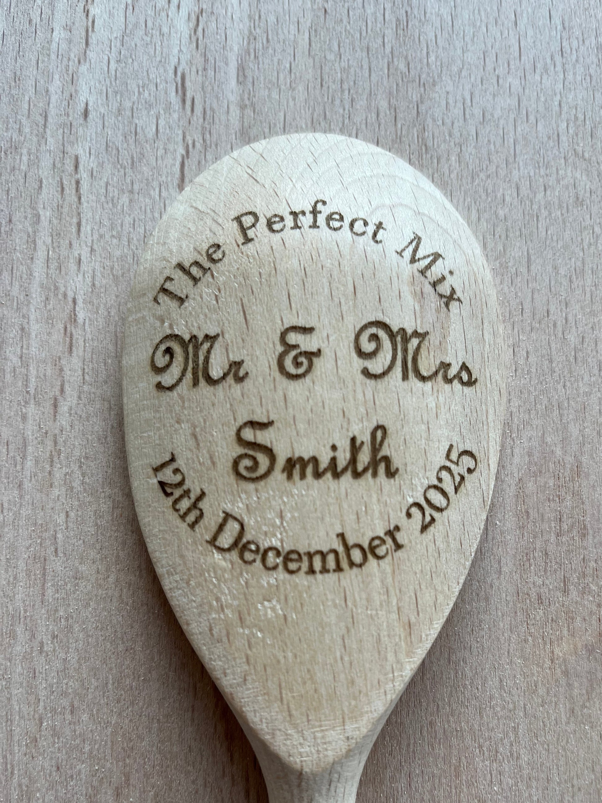 Wooden spoon with engraved text on a wooden surface