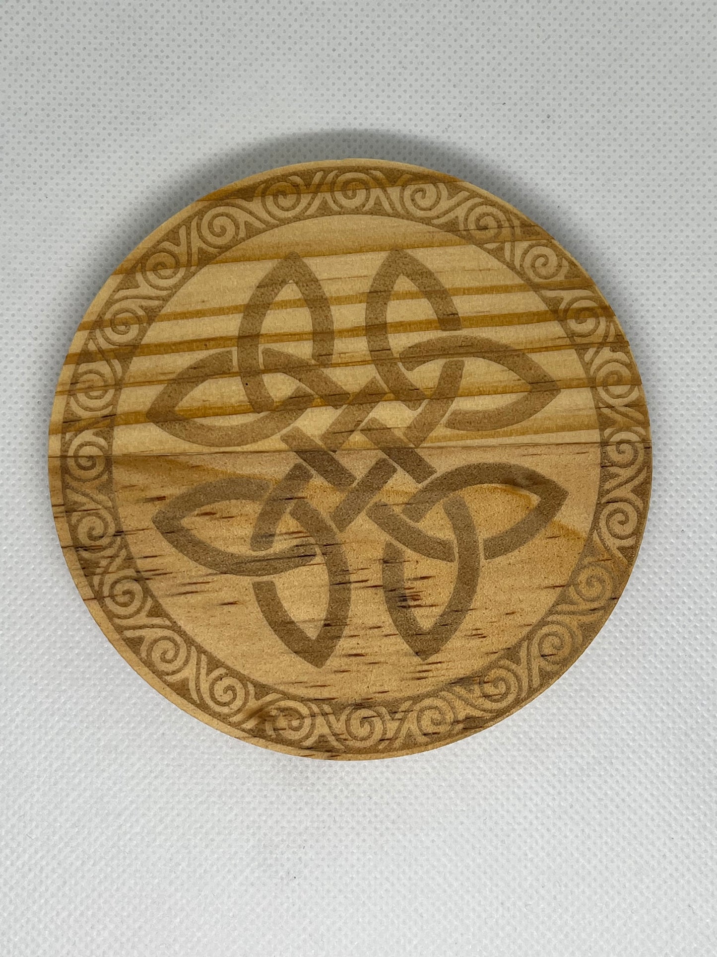 Wooden coaster with Celtic knot design on a light gray background