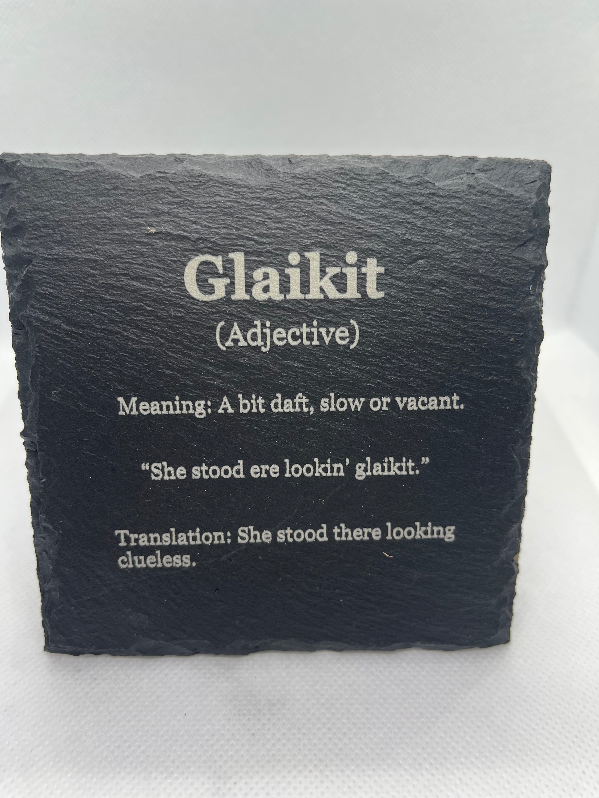 Slate coaster with engraved text on a white background