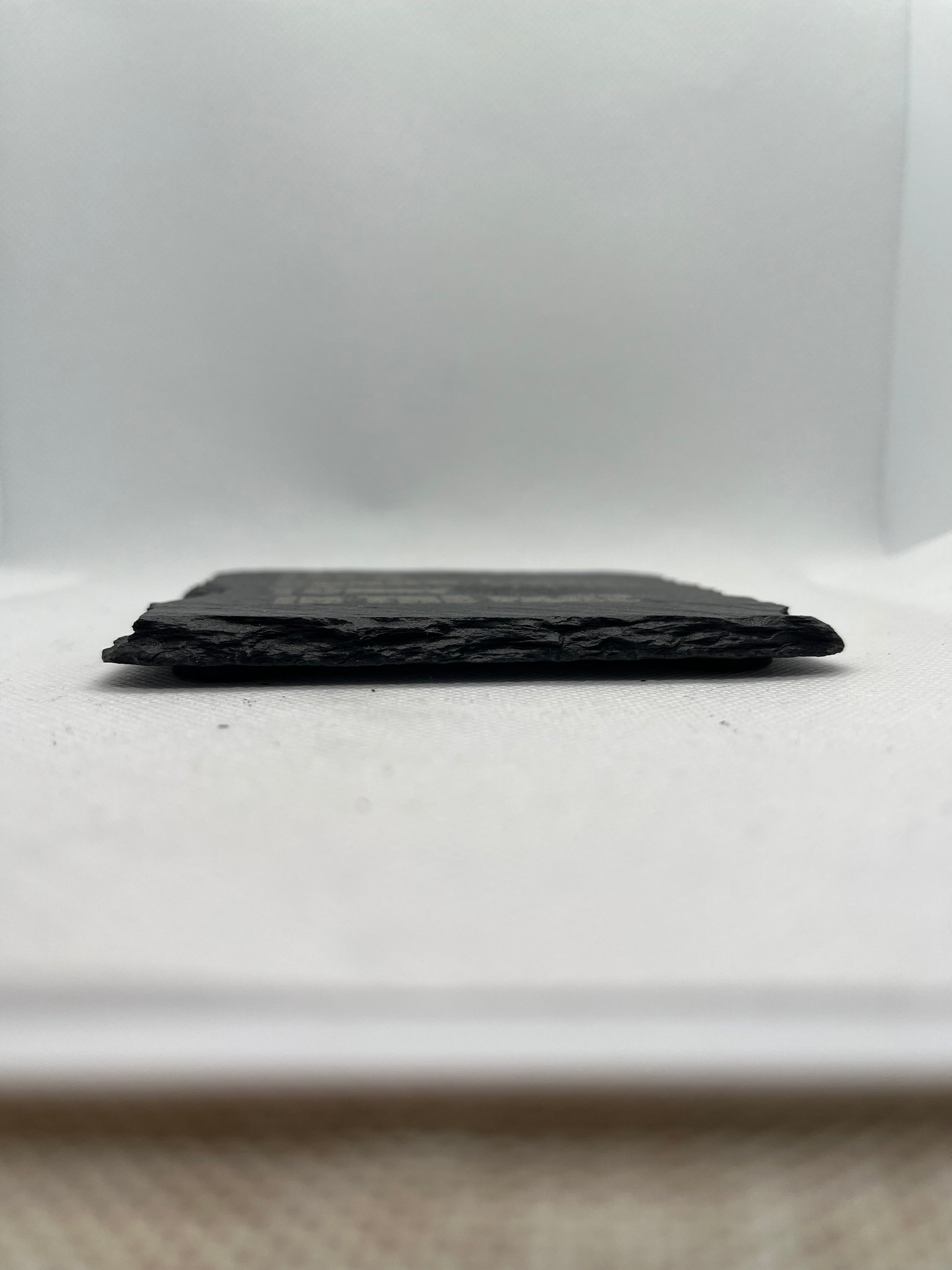 side-view-of-a-Black rectangular slate coaster on a white surface