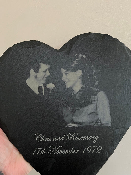 Heart-shaped slate with engraved photo of a couple and text on a beige background